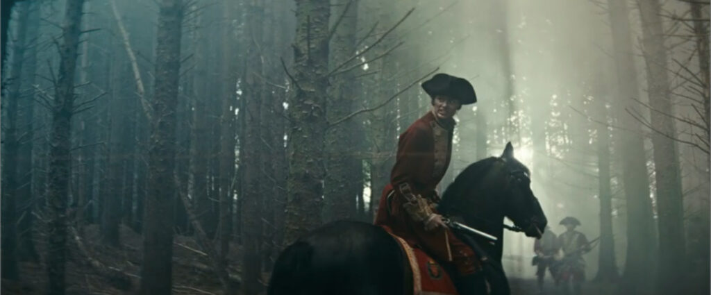 A young soldier in a red coat rides a black horse through a misty forest in Young Washington.